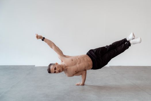 Athletic man in a one-handed handstand pose indoors, displaying strength and balance.