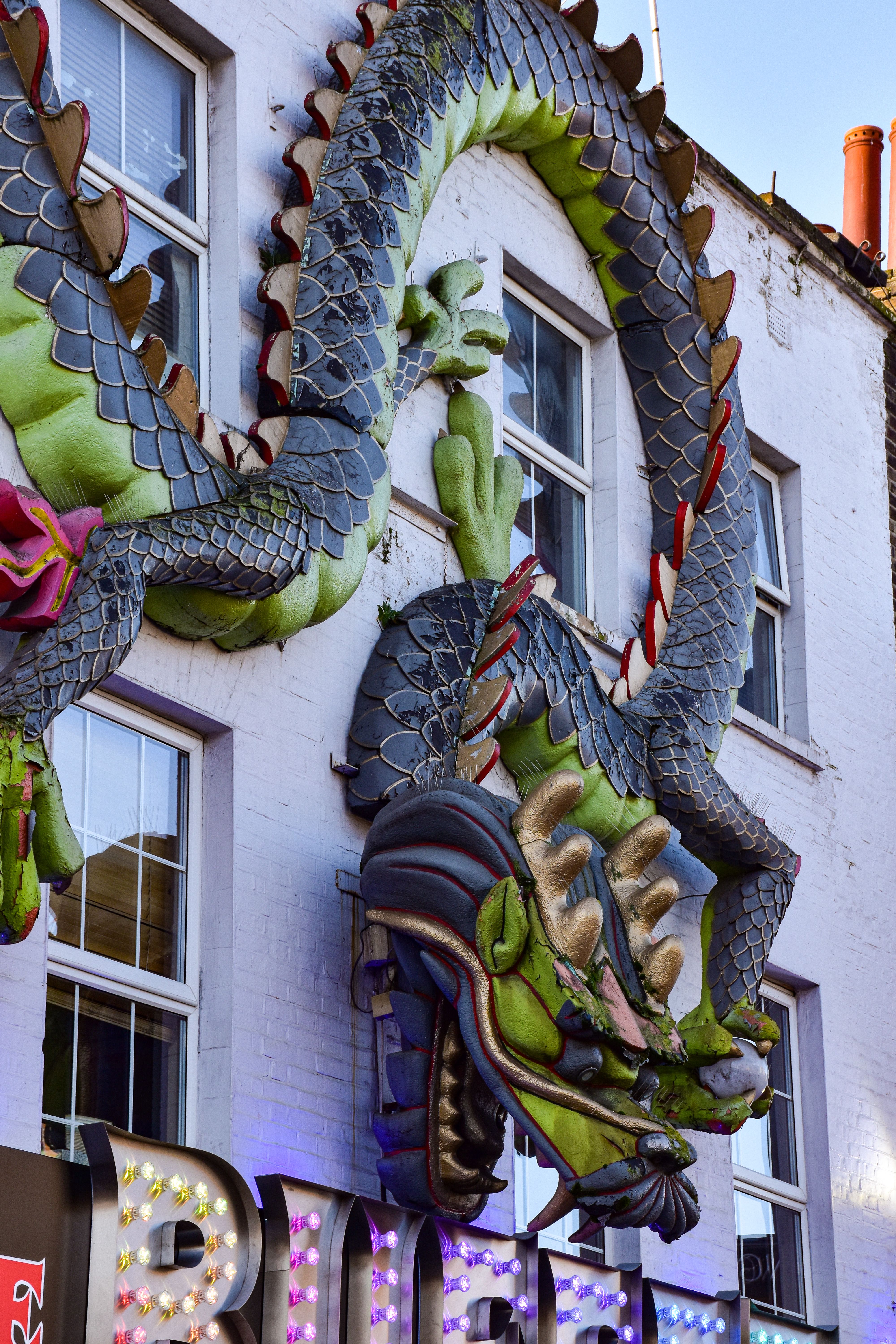 Vibrant dragon sculpture on display in London's bustling city streets.