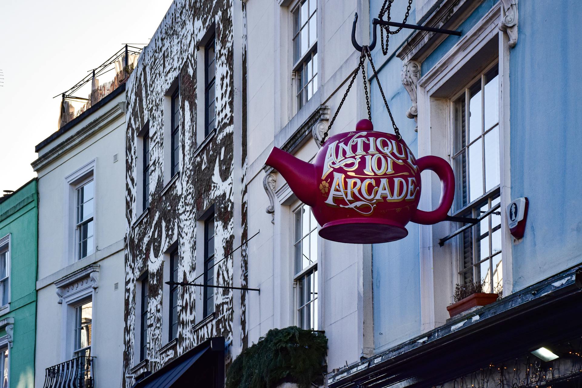 Vibrant teapot sign in a colorful London street, showcasing antique charm.