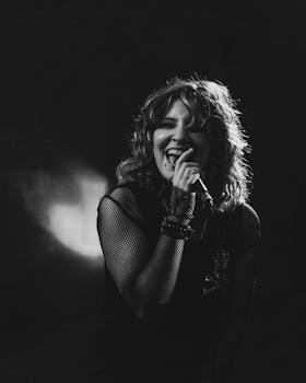 Black and white photo of a female rock singer passionately performing with a microphone.