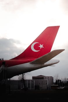 Close-up of a Turkish airline plane tail with the national flag design against a cloudy sky.