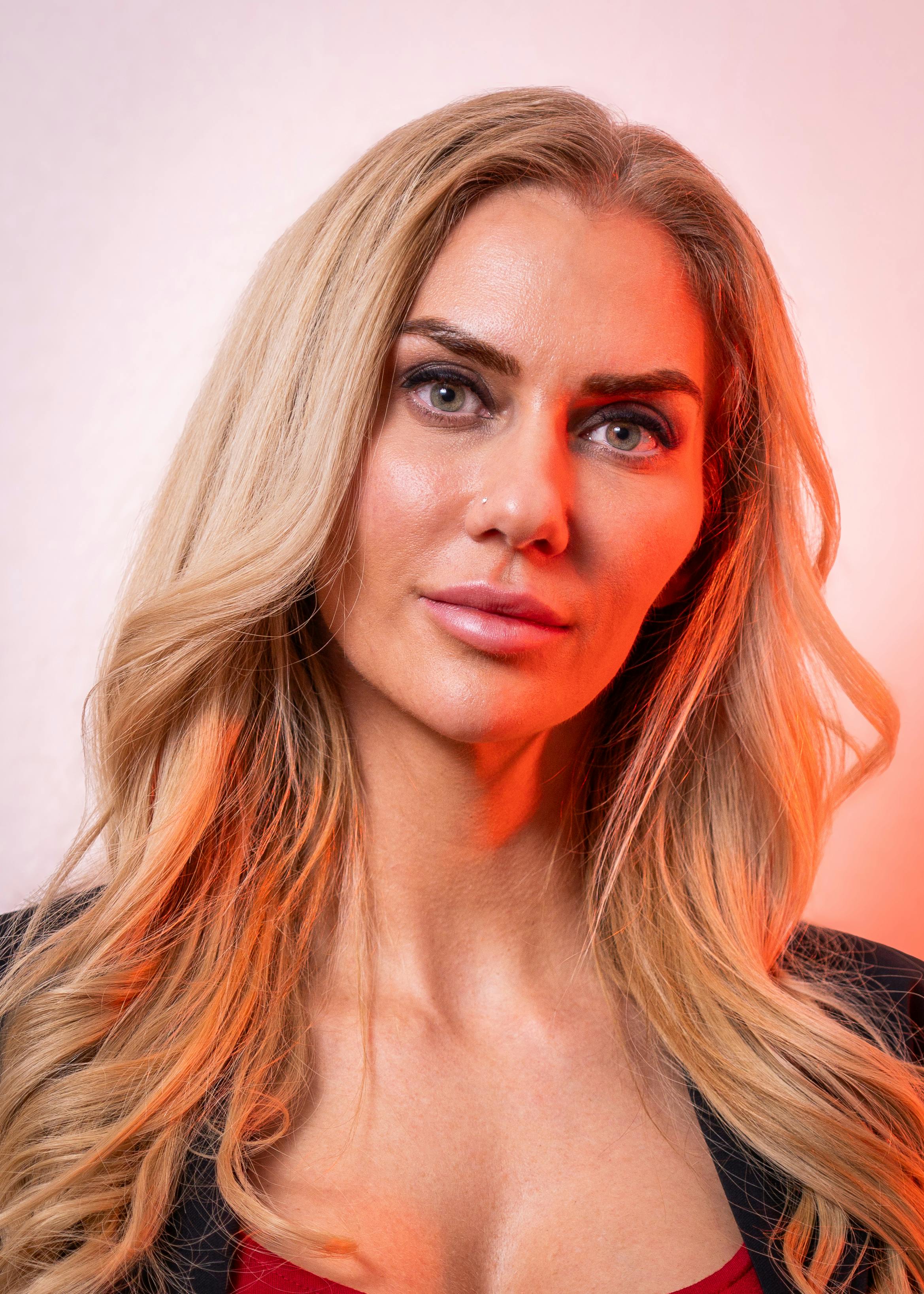 Close-up portrait of a woman with long blonde hair against a gradient background.