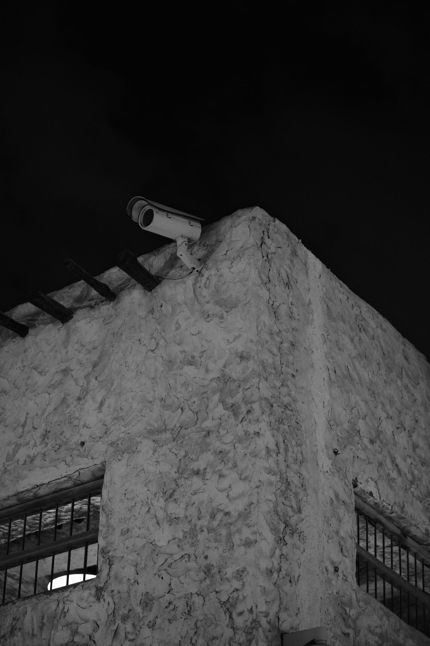 Caméra de surveillance à l'angle d'un bâtiment, photographie en noir et blanc
