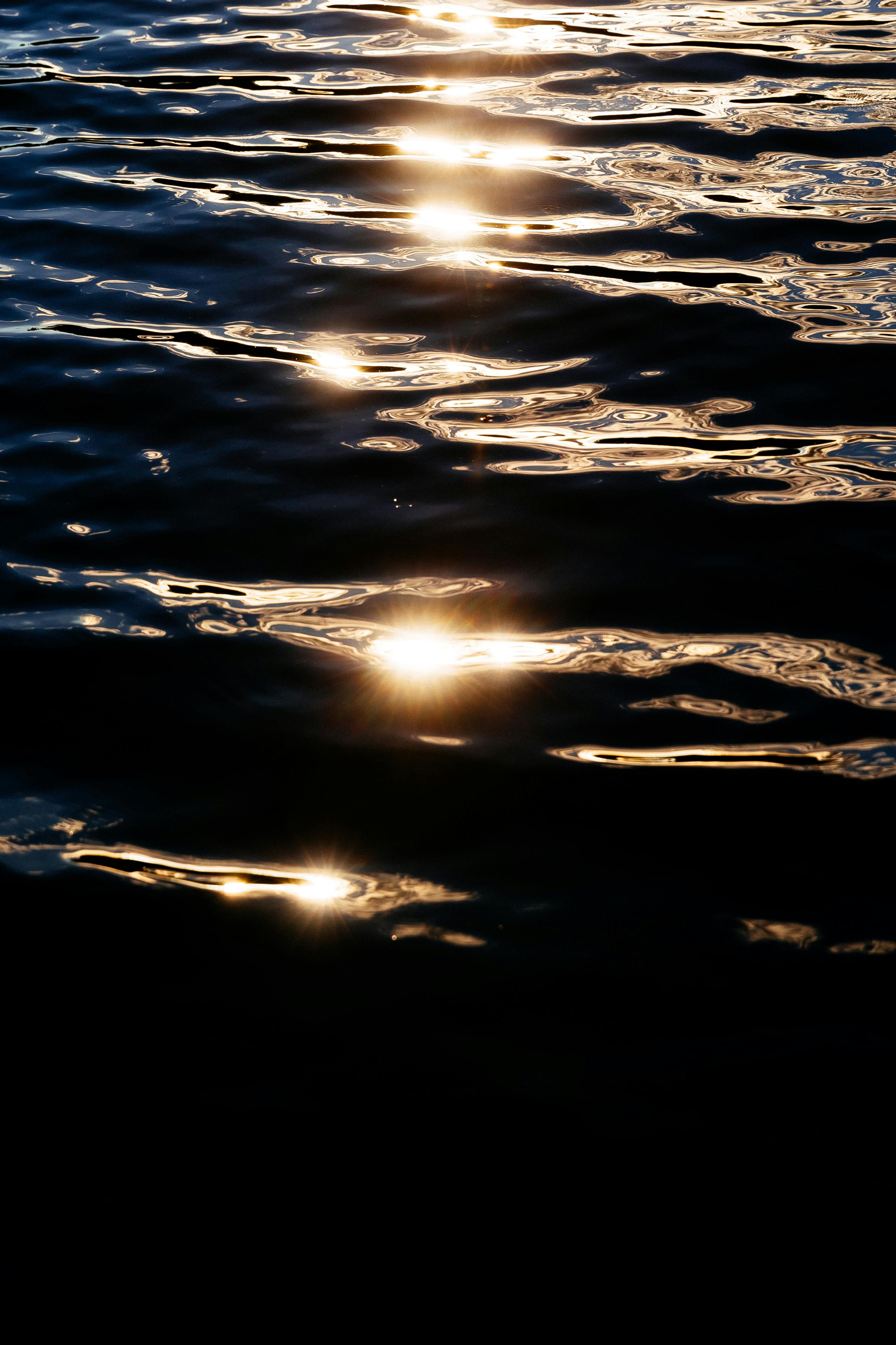 Sunlight reflecting on dark water creates tranquil patterns at sunset.