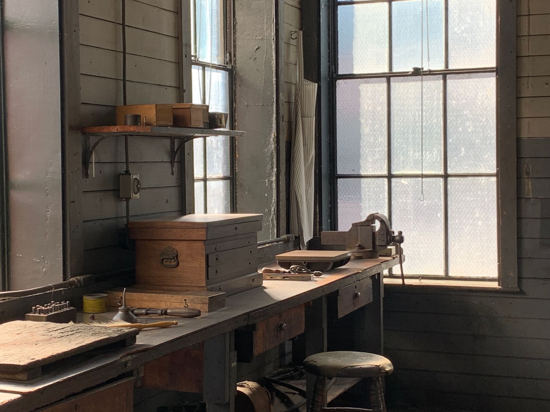 Sunlit historic workshop in New Jersey, showcasing vintage tools and wooden furniture.