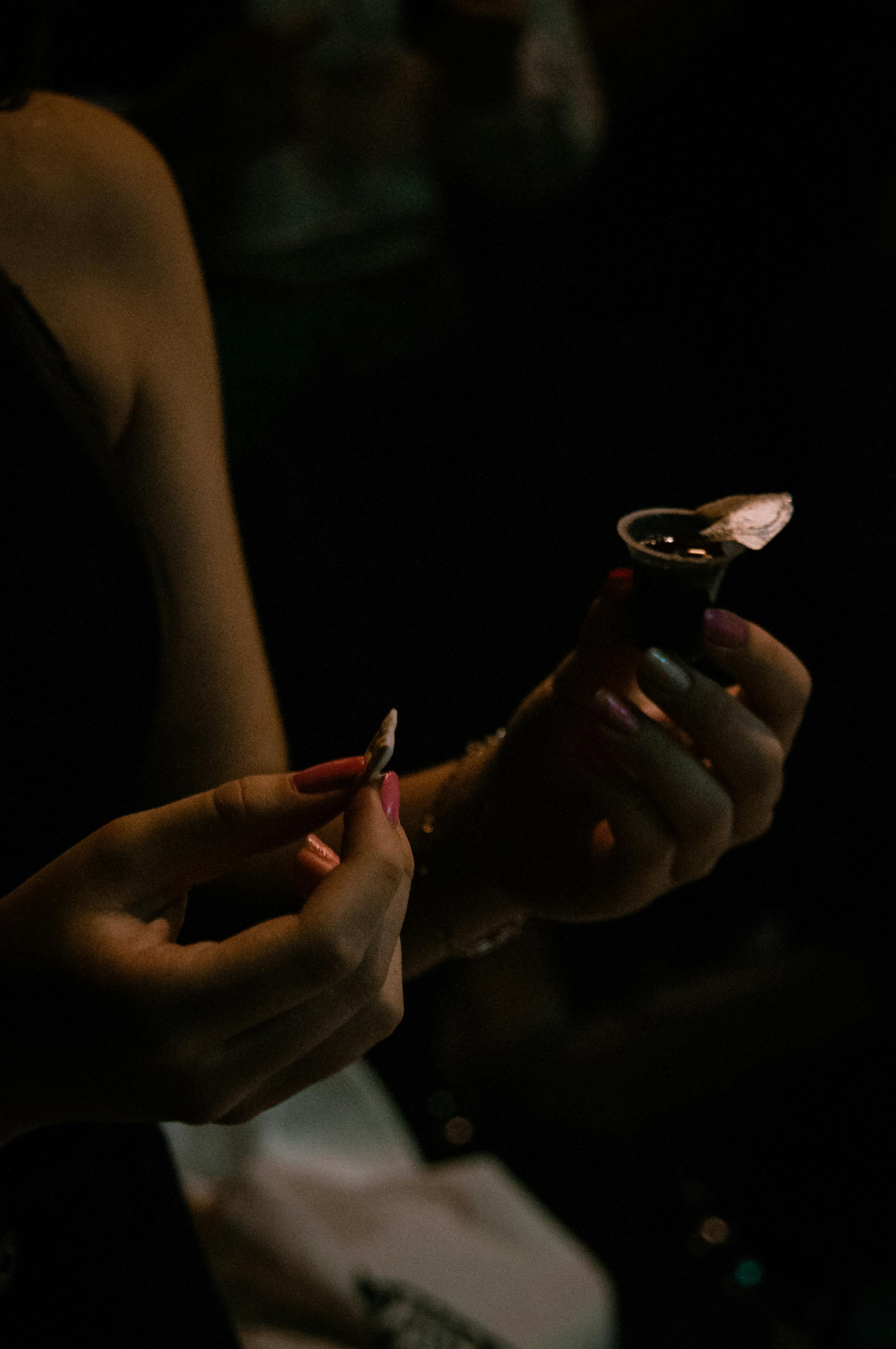 Gratis Primo piano di mani che tengono gli elementi della comunione in un ambiente scarsamente illuminato, creando un'atmosfera riflessiva. Foto a disposizione