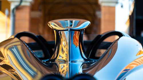 Free A detailed view of a metallic racing car part with urban reflections. Stock Photo