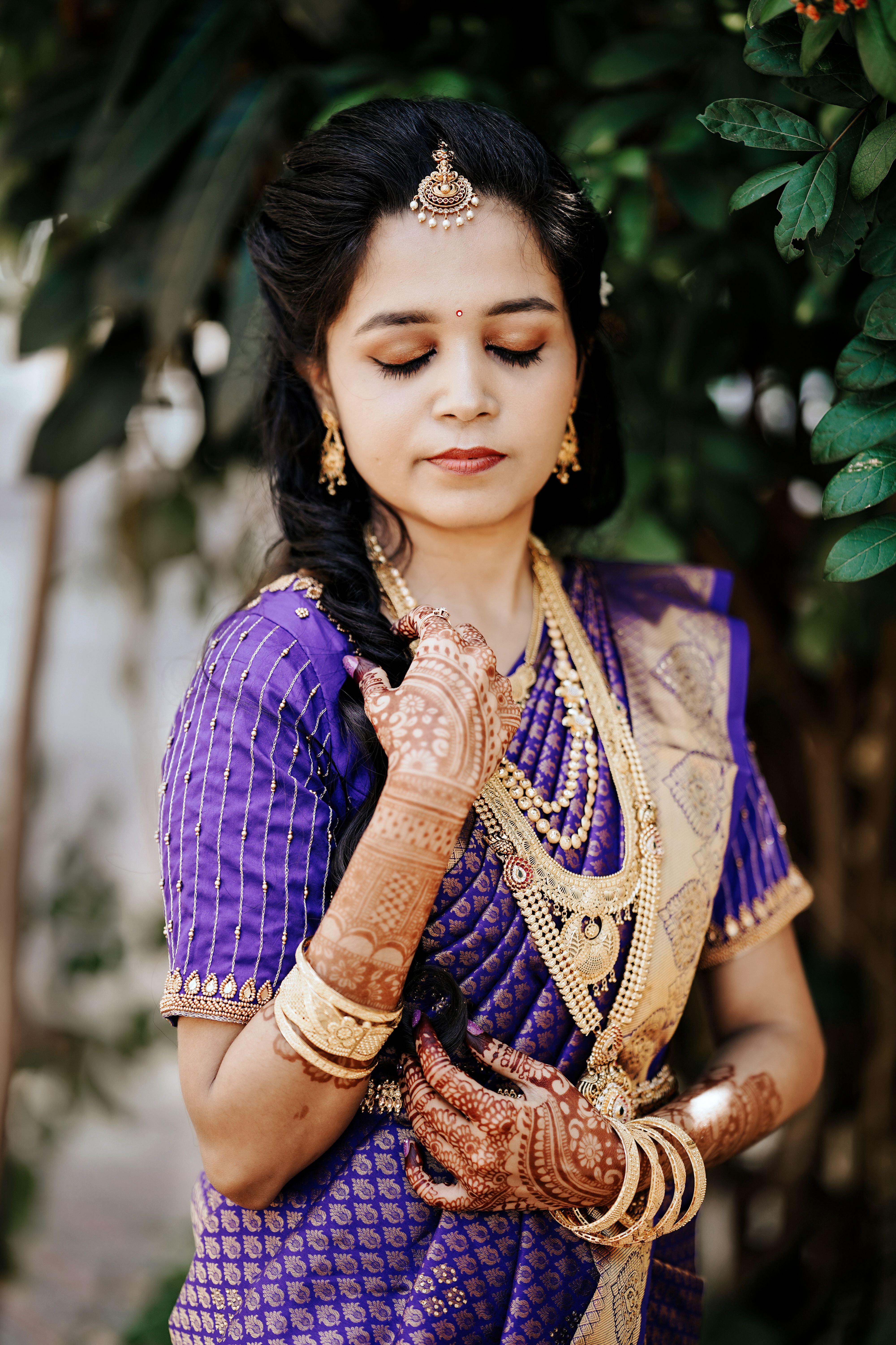 South Indian bride in purple silk saree with mehndi and gold jewellery