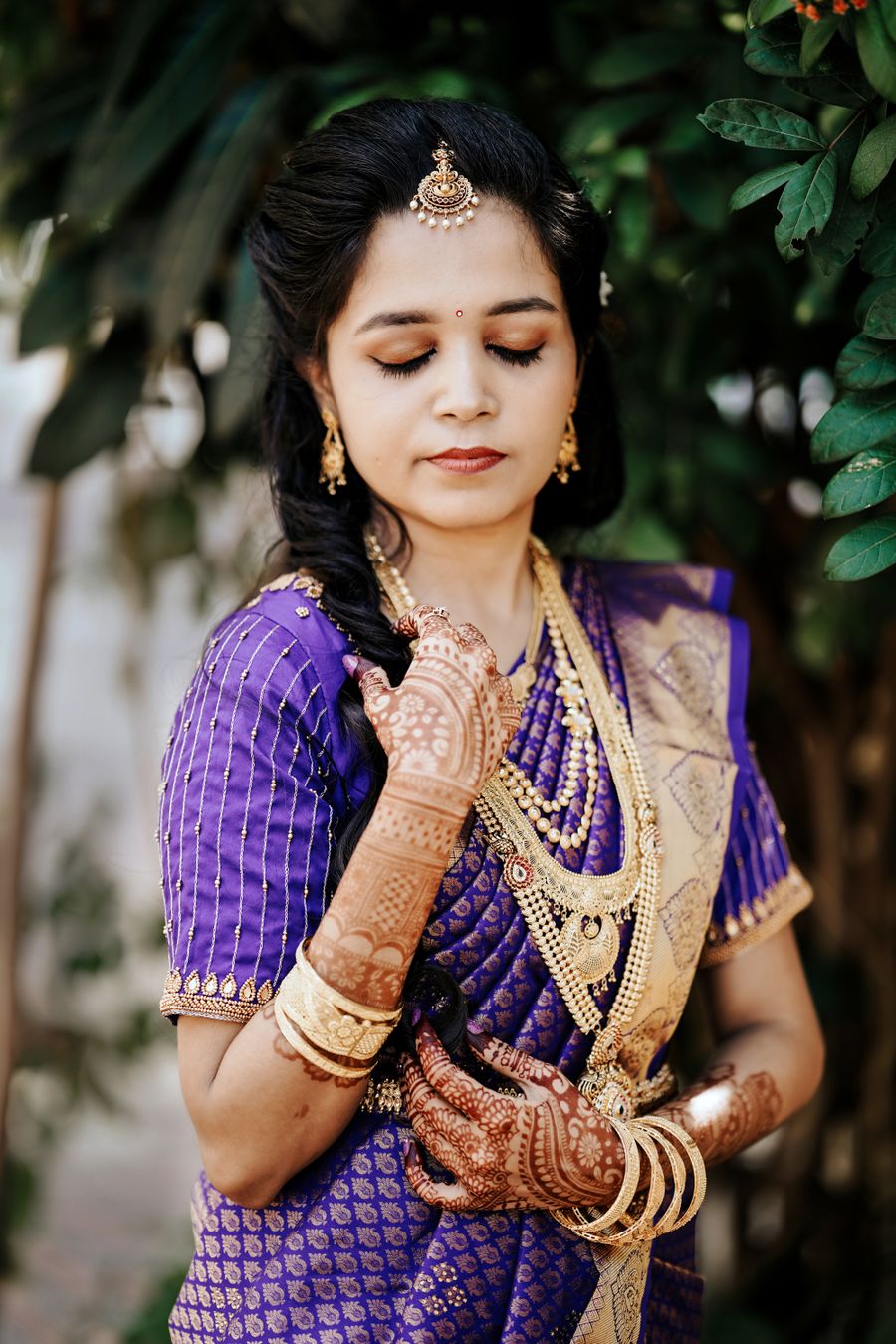 South Indian bride in purple silk saree with mehndi and gold jewellery