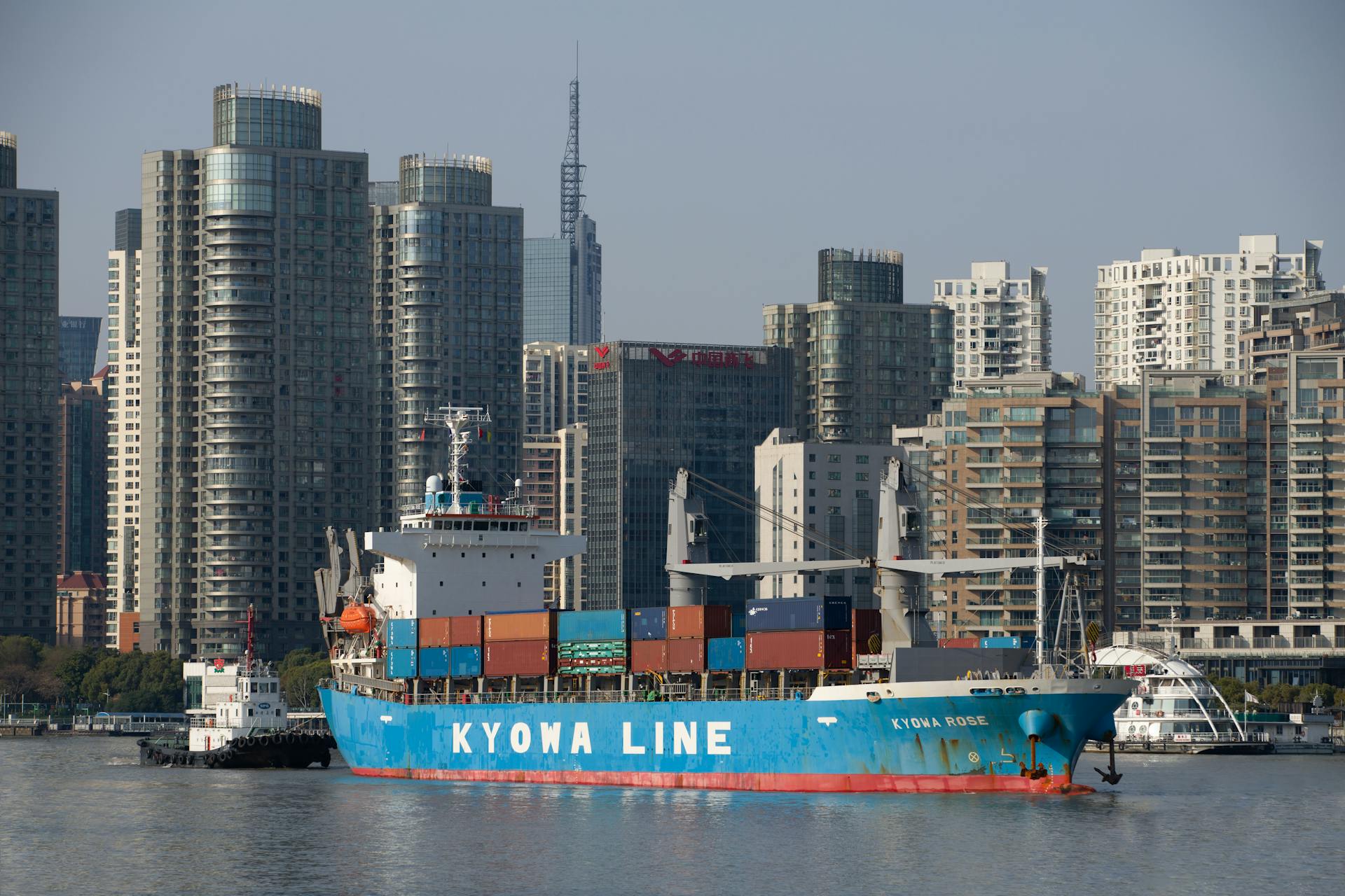 A blue container ship in front of a modern urban skyline, reflecting global trade.