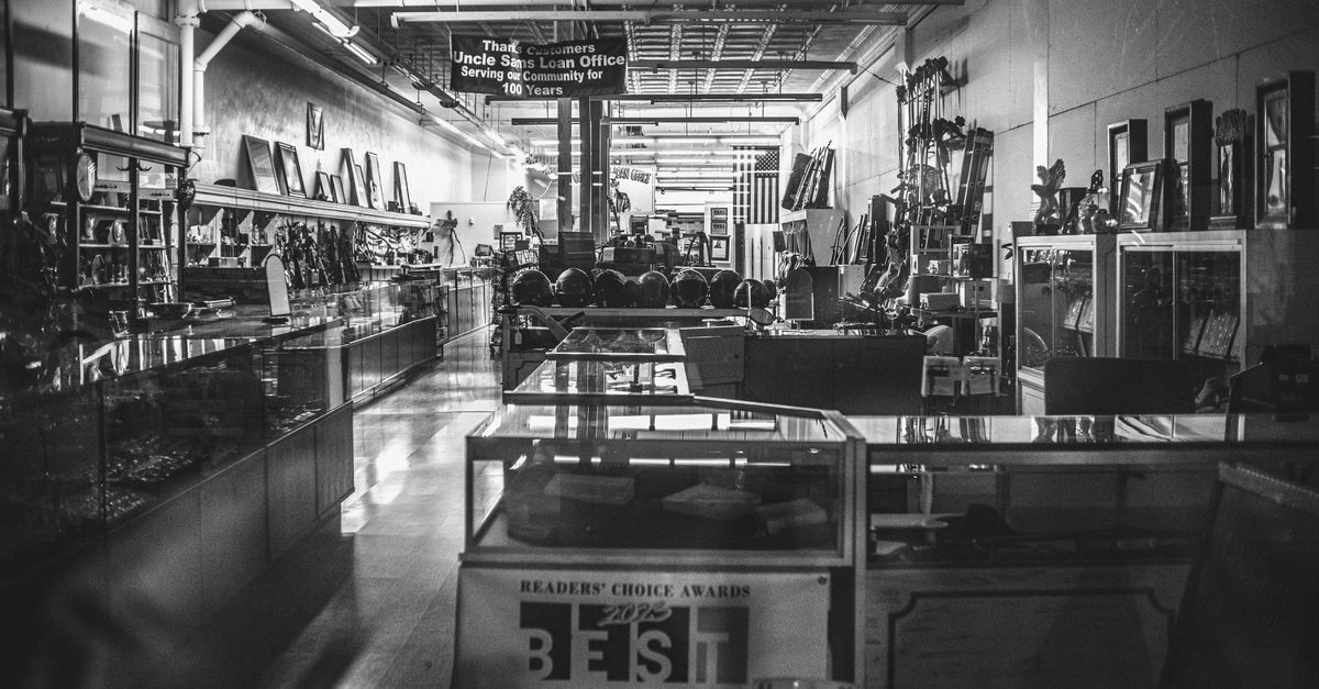 Black and white photo of the interior of an antique pawn shop filled with various items.