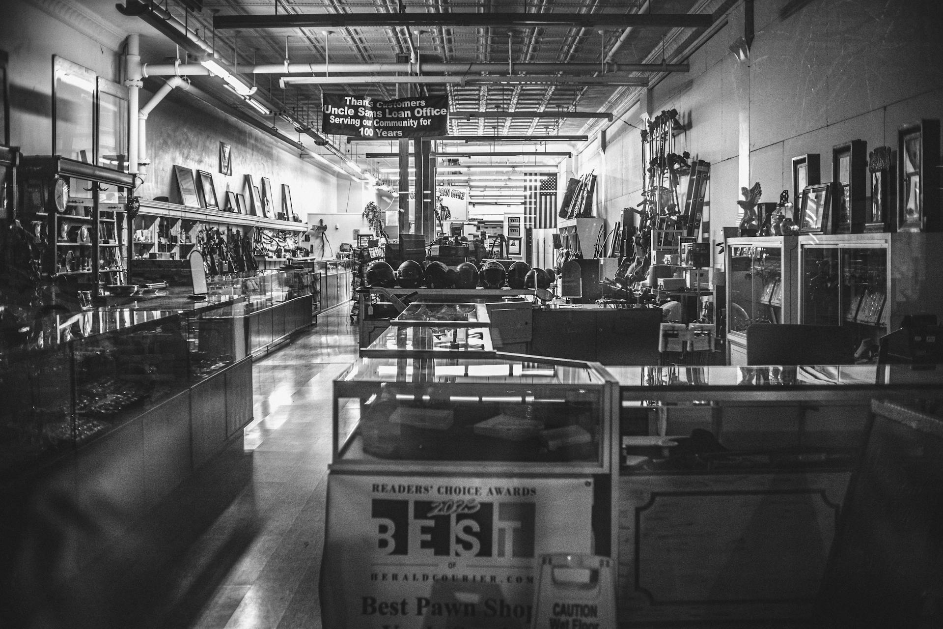 Black and white photo of the interior of an antique pawn shop filled with various items.