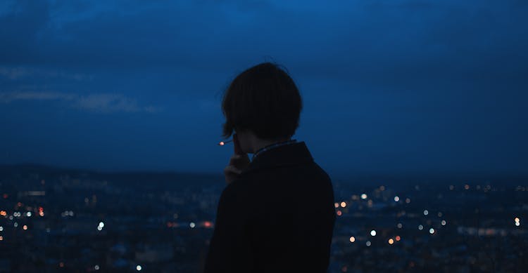 Person Smoking Across City Building During Nighttime