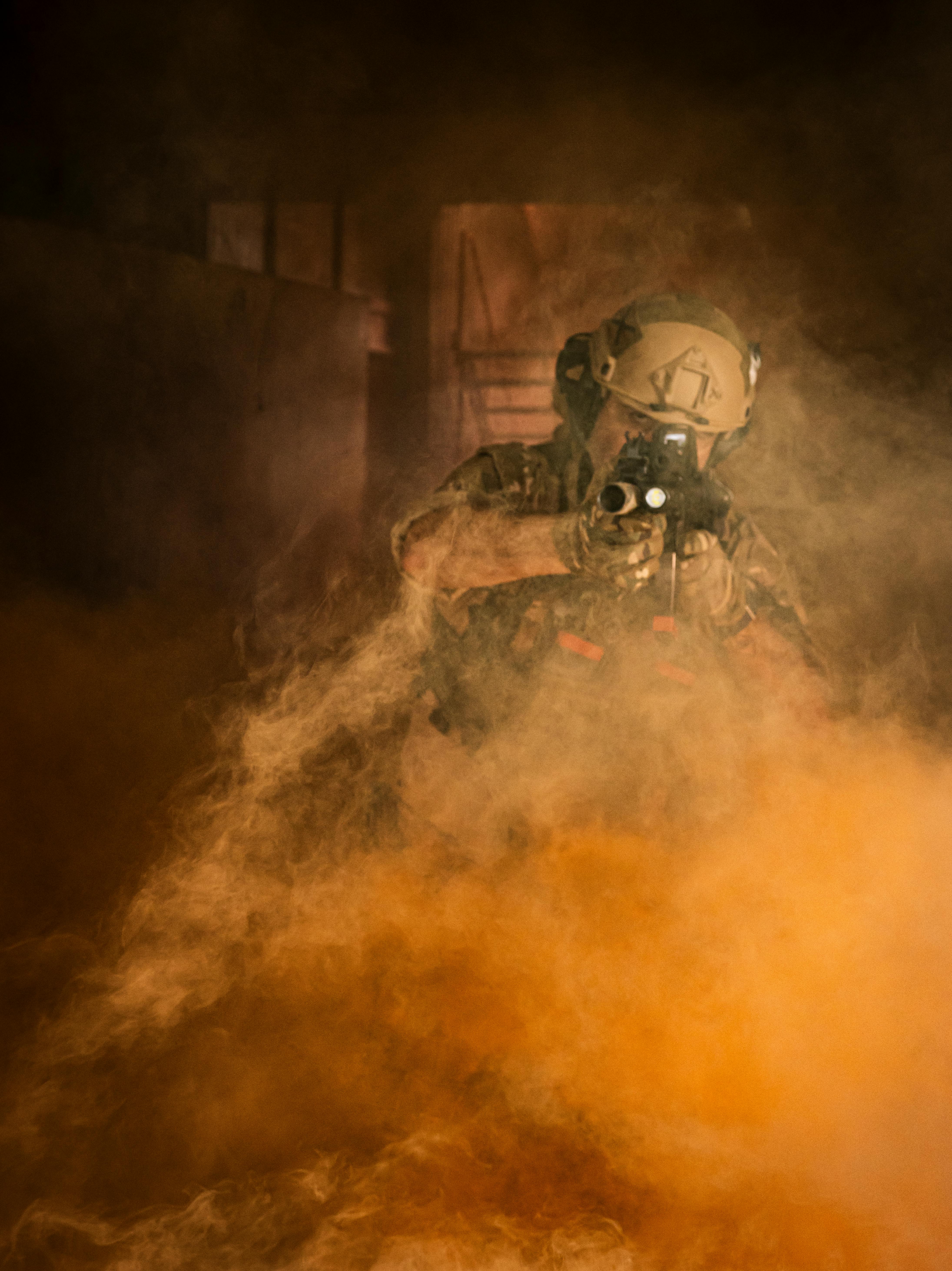 A soldier in tactical gear moving through a room filled with dense smoke, creating a dramatic scene.