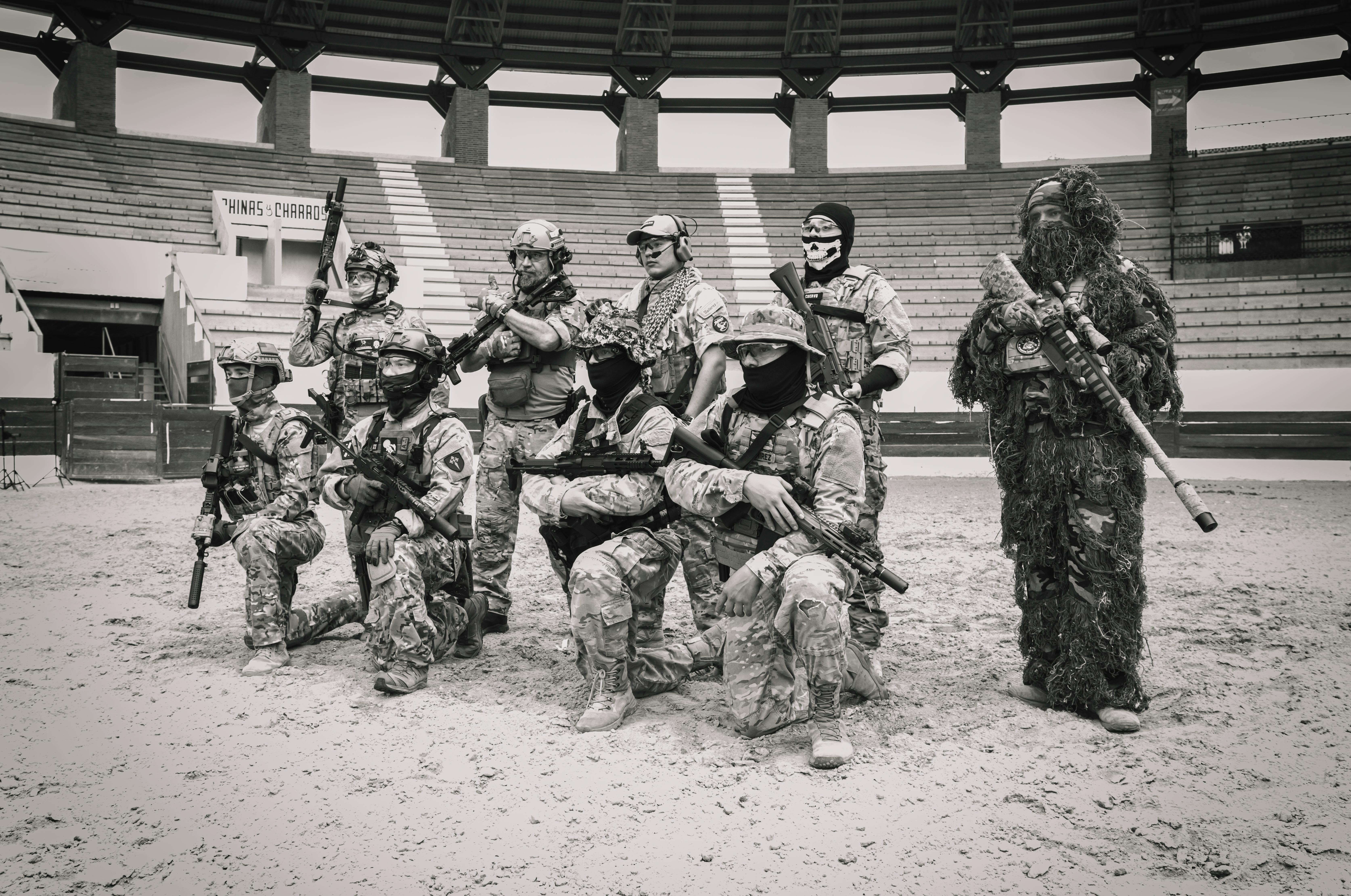 Group of soldiers in tactical gear posing in an arena for a military drill.