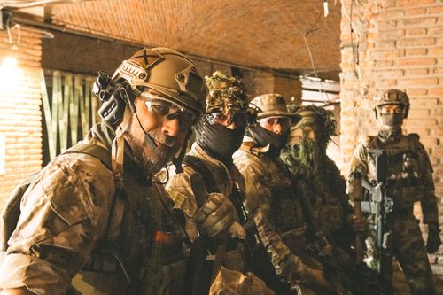 Free Team of soldiers in camouflage and helmets gathered indoors for a briefing. Stock Photo