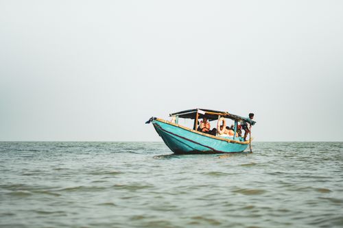 Free A serene boat with passengers floating on calm waters, creating a peaceful scene. Stock Photo