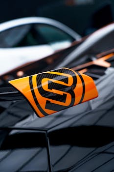 Orange and black badge on a sleek supercar, highlighting design and luxury.