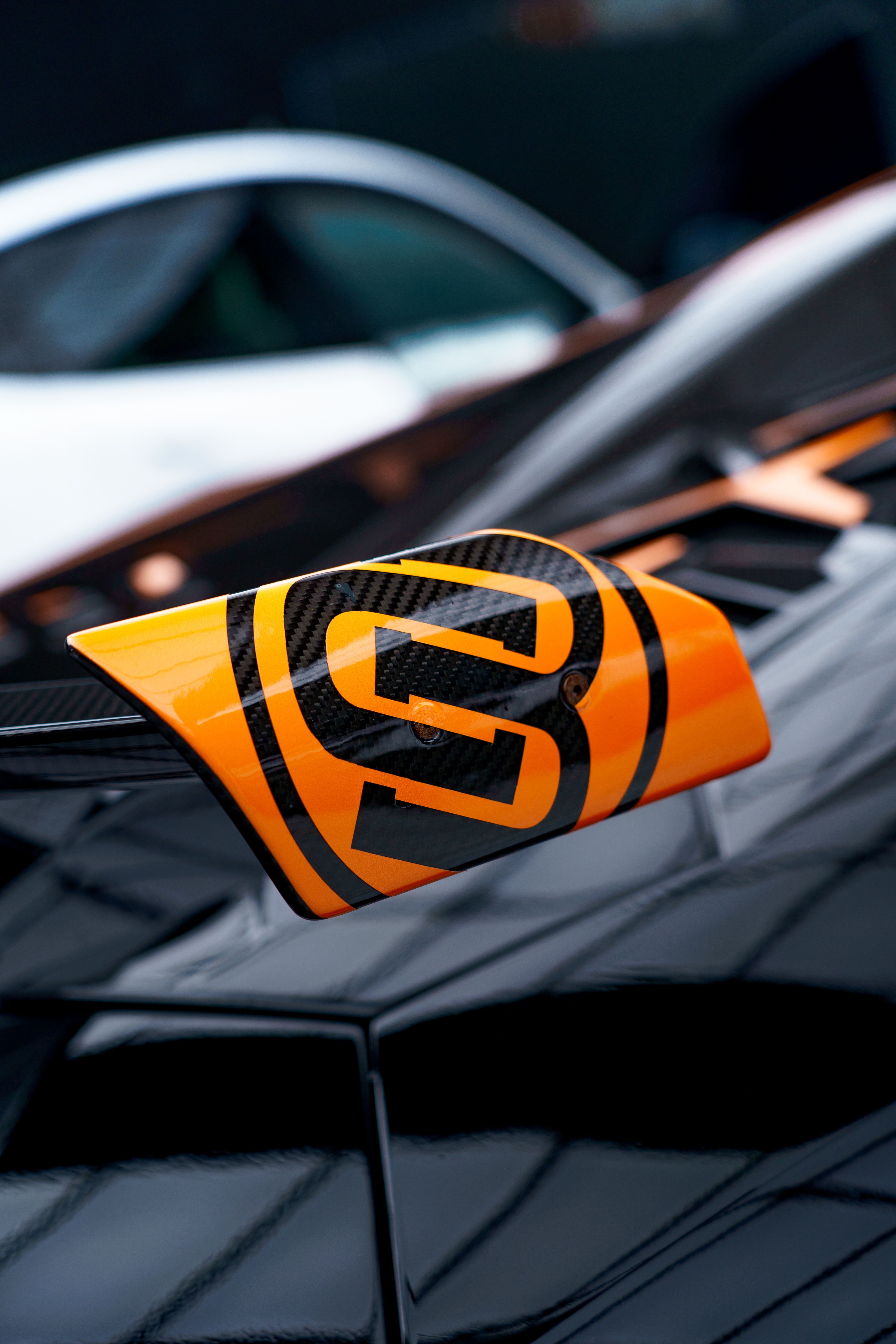 Close-Up of Orange and Black Supercar Badge · Free Stock Photo