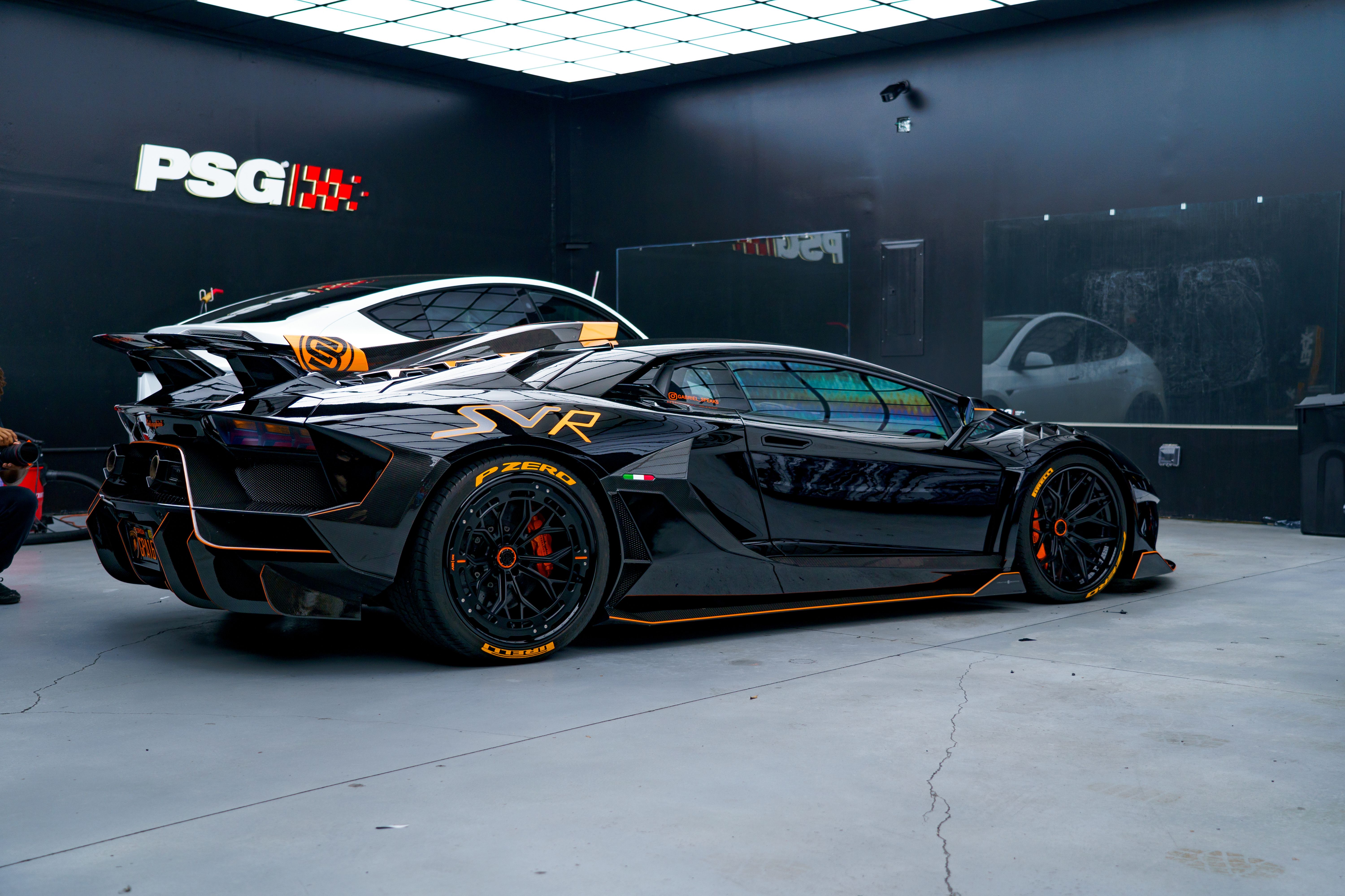 Black sports car with aerodynamic design in a sleek modern garage environment.