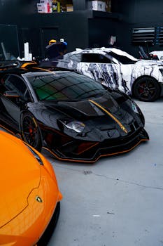 Black and orange luxury sports cars in a sleek, urban garage setting.