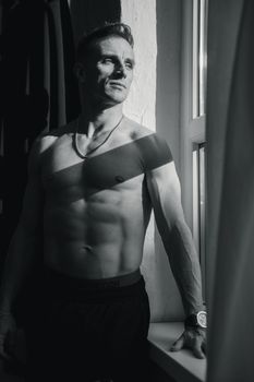 Dynamic black and white portrait of a male model posed by a window in Berlin.