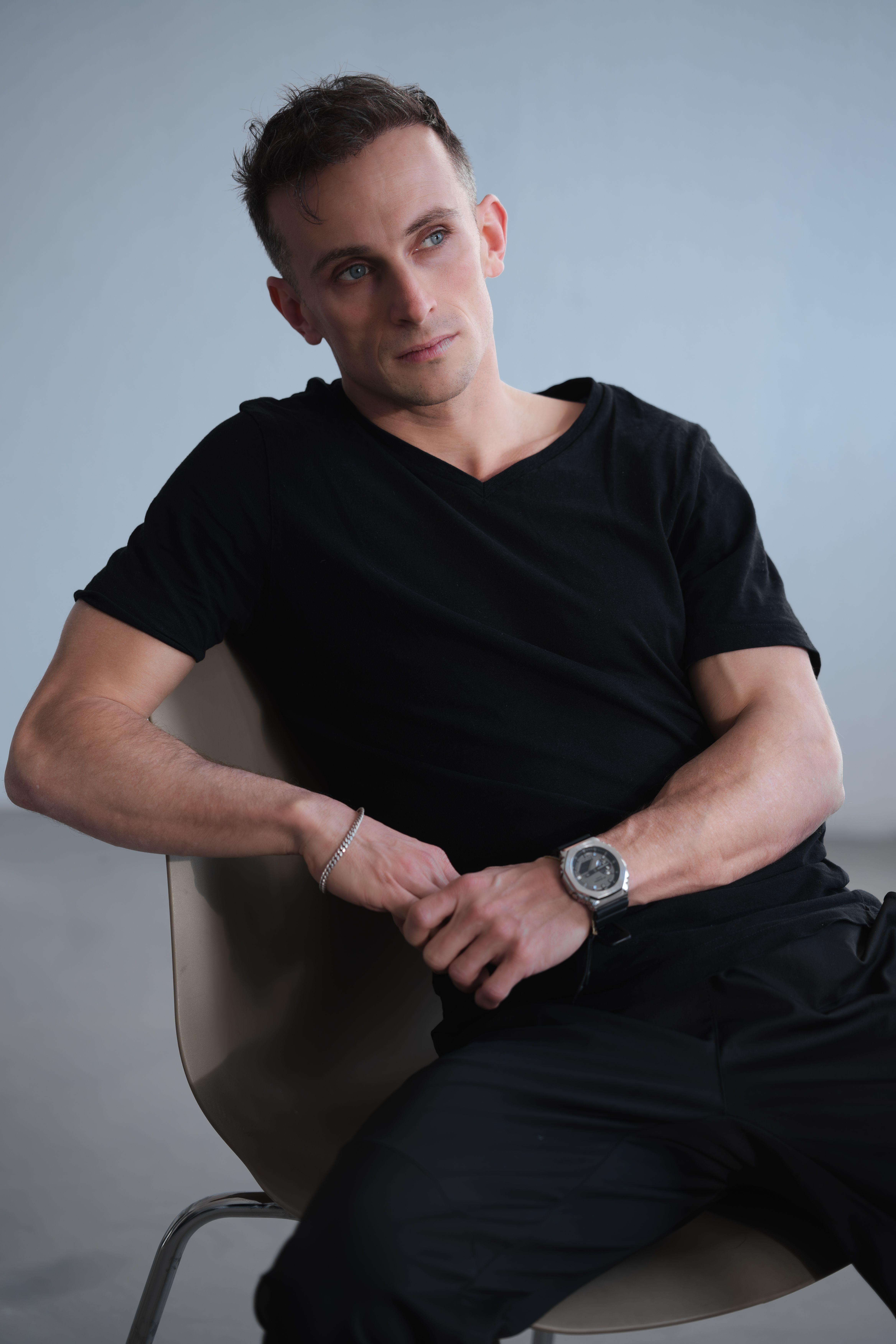 Portrait of a young man seated casually in a Berlin studio setting, exuding modern elegance.