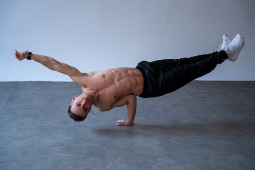 Athletic male dancer performing a one-arm handstand in a Berlin studio.