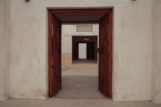 Rustic wood doors open into a historical building corridor, showcasing architectural charm.
