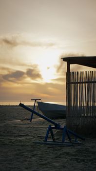 A serene sunset view over a beach with a playground and bamboo hut in Durrës, Albania.