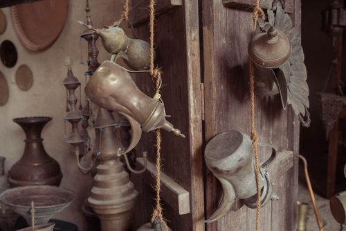 Free Artistic arrangement of rustic brass teapots hanging on a wooden door in a vintage setting. Stock Photo