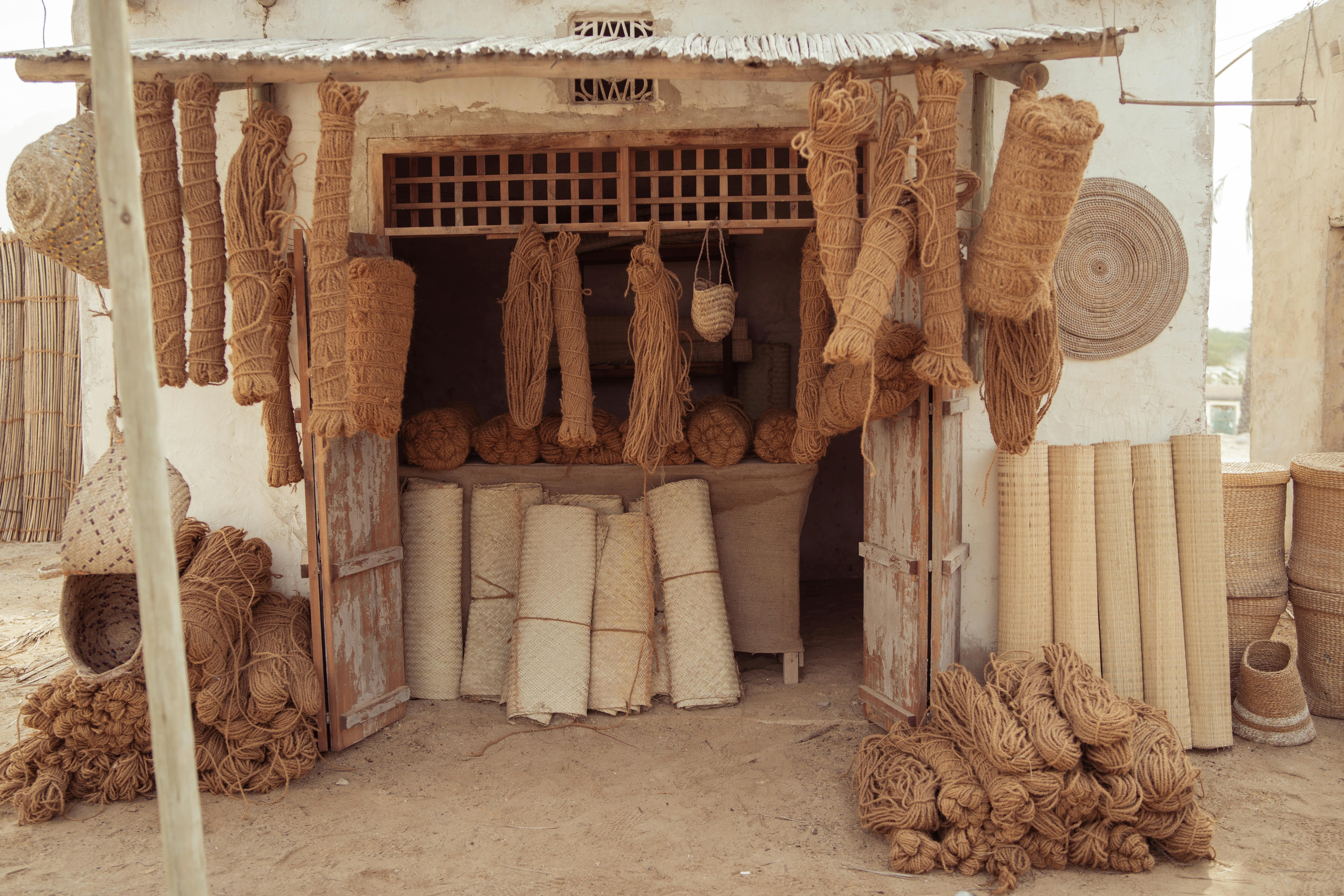 An outdoor display of handcrafted mats, ropes, and rugs in a rustic setting showcasing traditional artisanal skills.