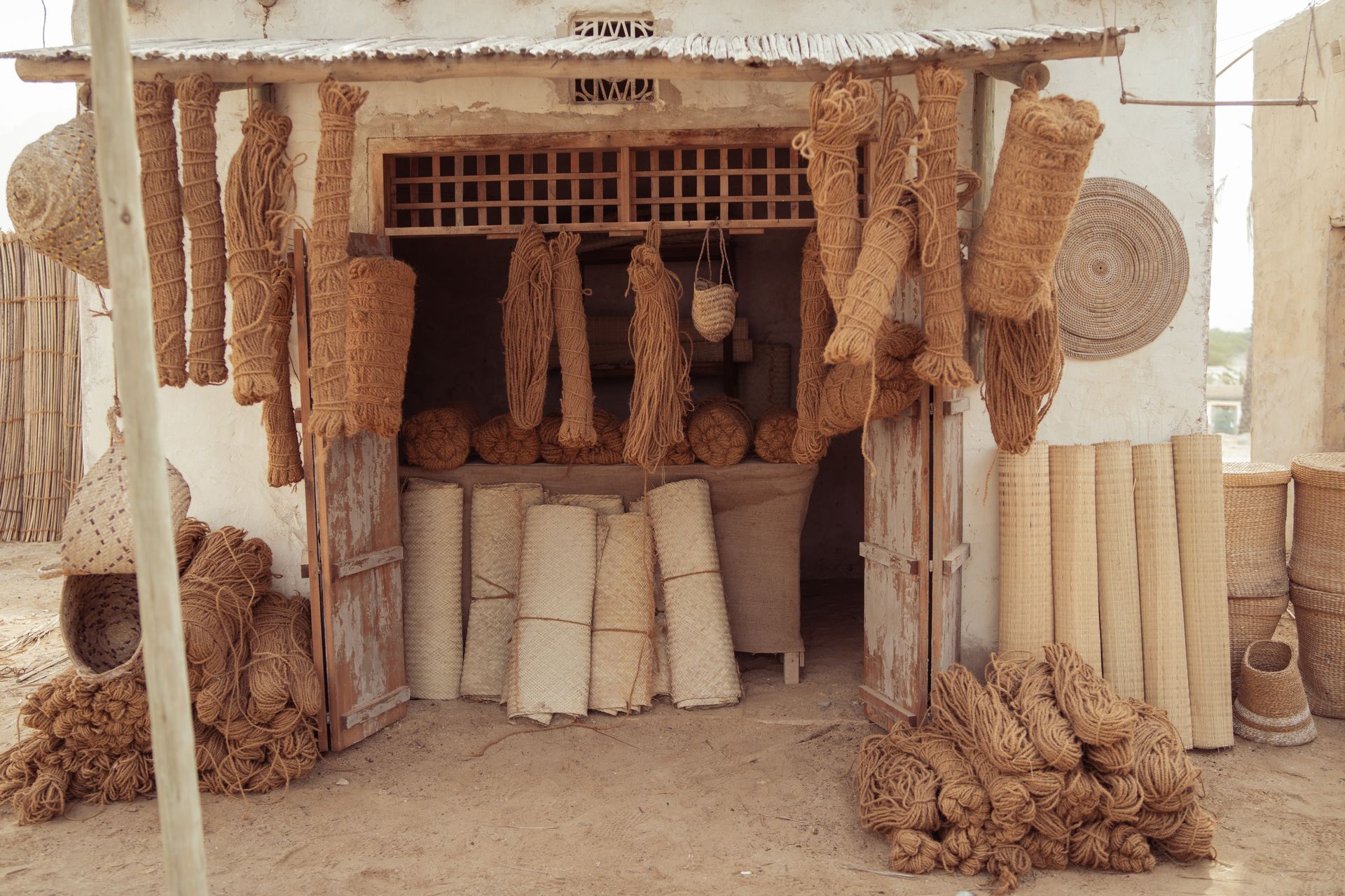 An outdoor display of handcrafted mats, ropes, and rugs in a rustic setting showcasing traditional artisanal skills.