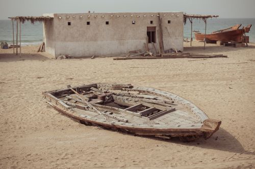 Free Old wooden boats on a sandy beach near a rustic hut by the sea. Stock Photo