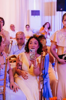 A lively indoor wedding celebration with guests in elegant dresses, capturing joyful moments.