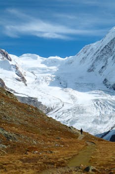 Stunning view of the Swiss Alps with a lone hiker and a majestic glacier.