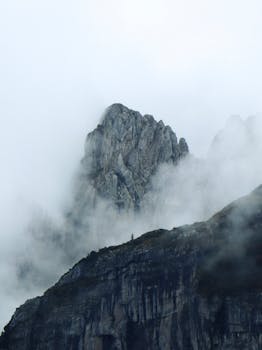 Dramatic view of a misty mountain peak in the Swiss Alps shrouded in clouds.