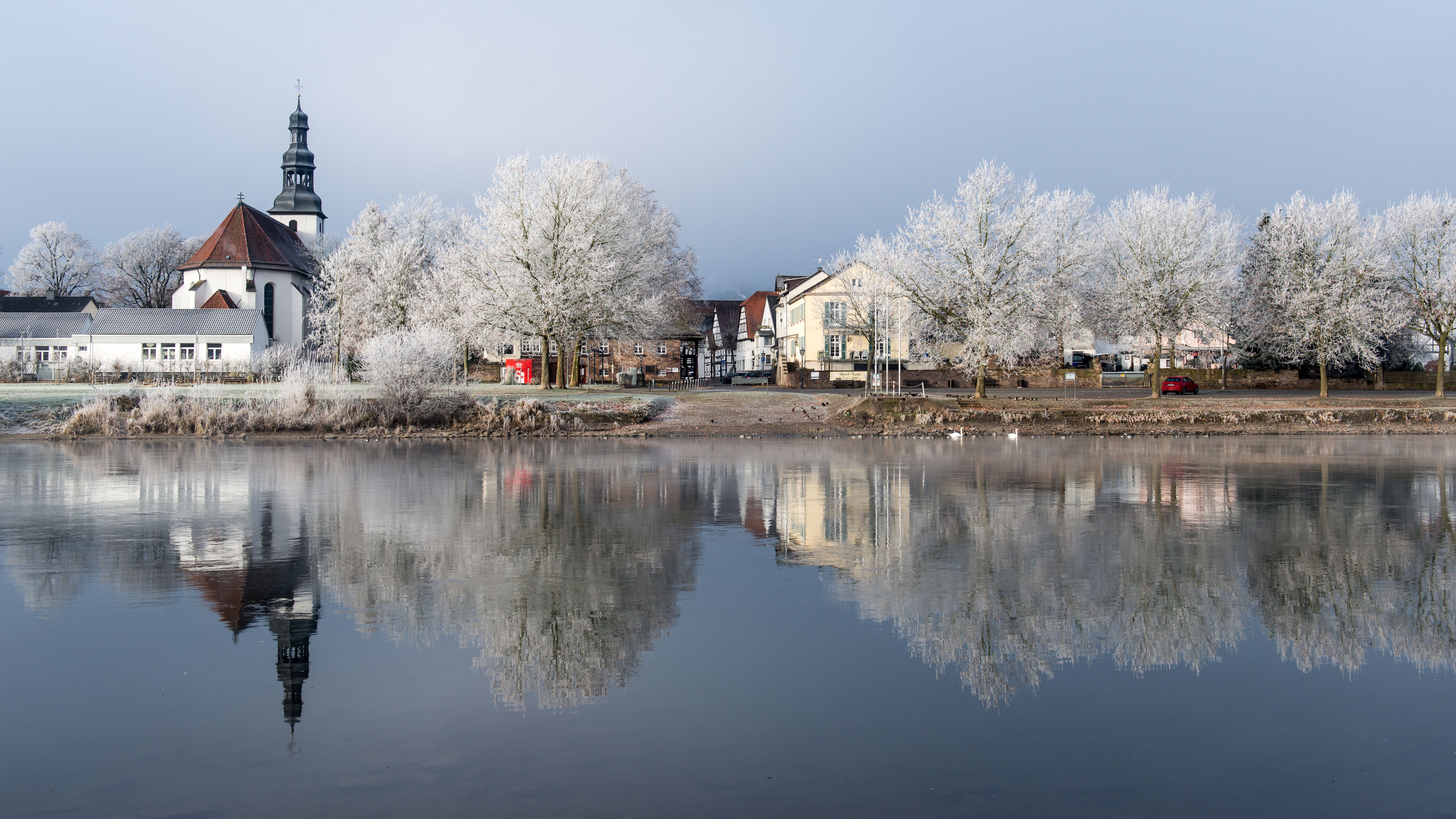 Bucolic winter scene of Beverungen, Germany with frosty trees and a peaceful riverfront.