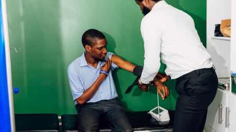 A healthcare professional checks a patient's blood pressure in a clinic in Lagos, Nigeria.