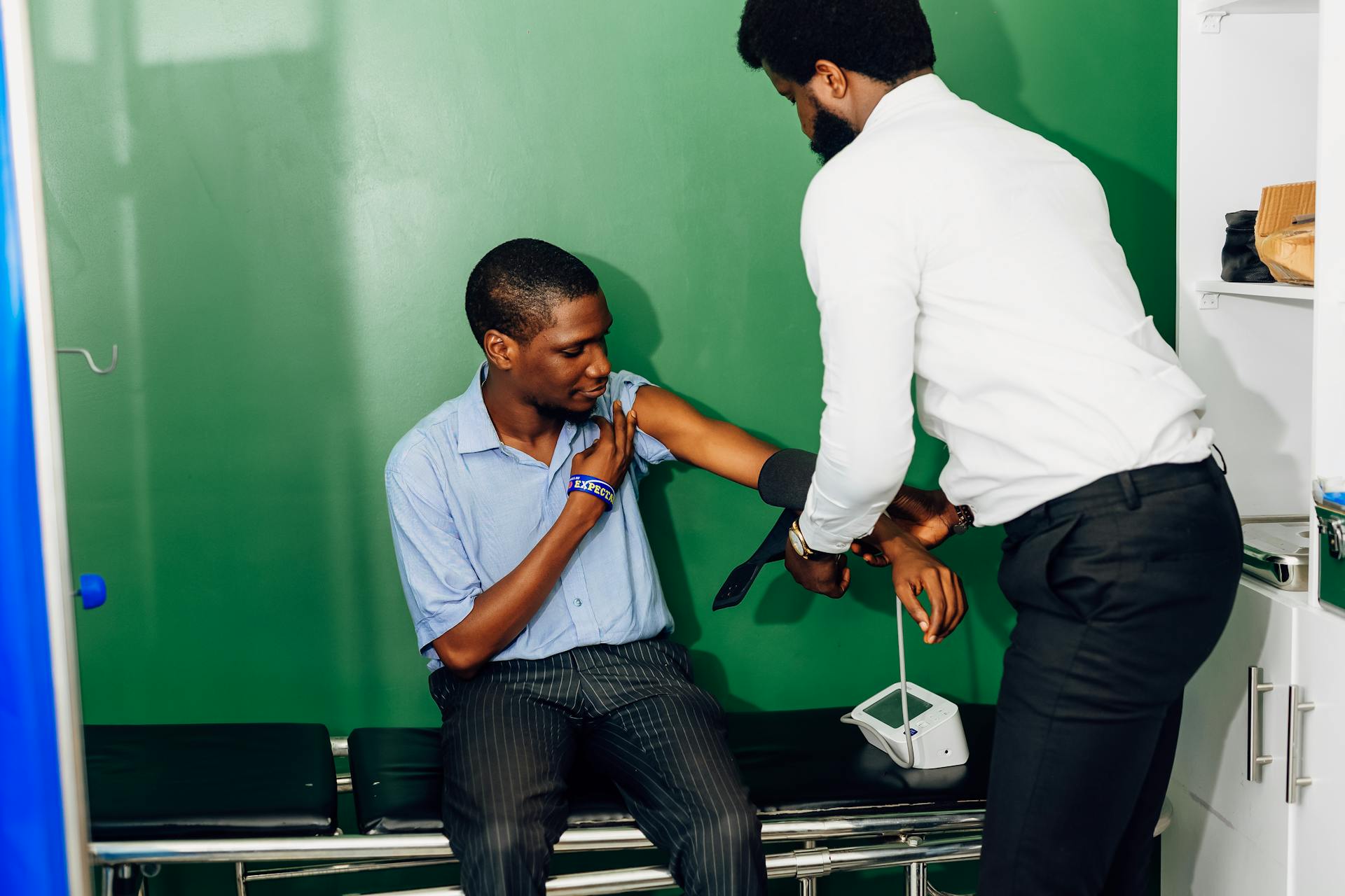 A patient sitting on an hospital bed to have his blood pressure checked by a doctor.  Find more afro-centric images at www.ninthgrid.com