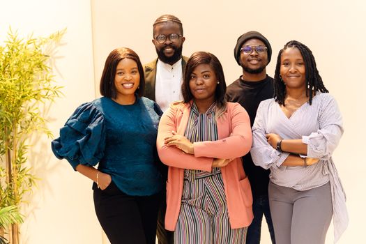 A diverse group of business professionals smiling confidently indoors.