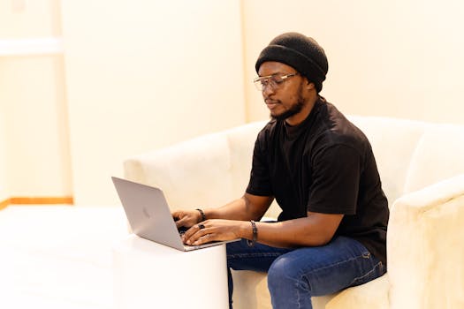 Adult male in Lagos, Nigeria working on a laptop, focusing on productivity in a modern indoor workspace.