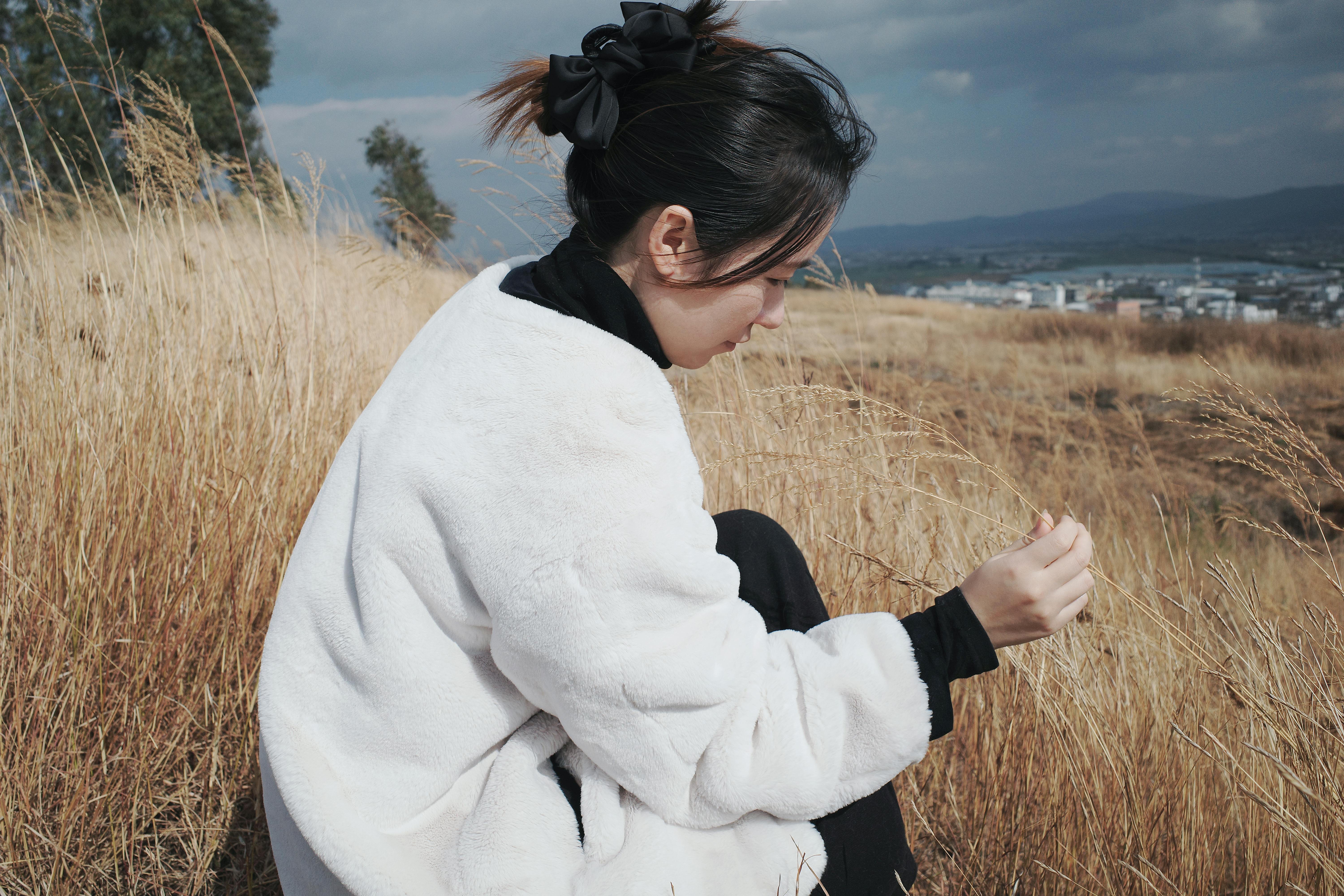 woman in white coat exploring dry grassland