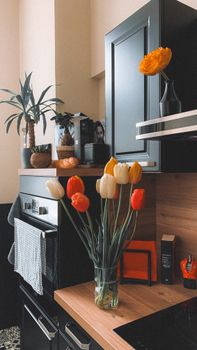 Cozy kitchen with vibrant tulips and modern decor on a wooden countertop.