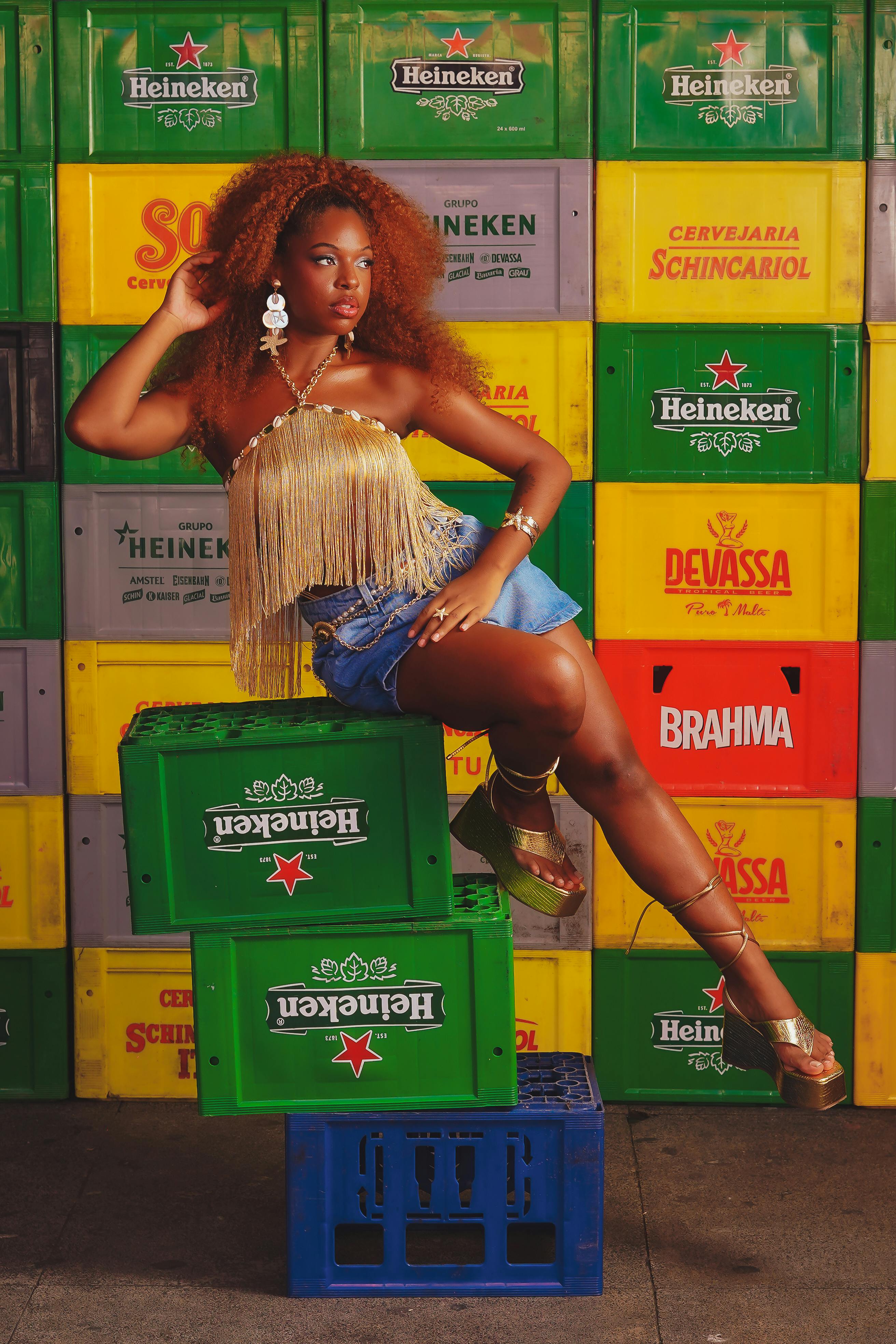 Fashionable woman in fringe top posing against colorful beer crates.