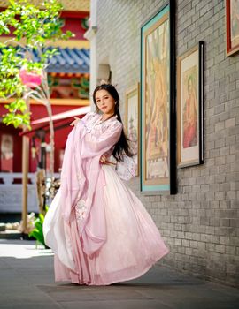 An elegant woman in traditional Hanfu dress posing gracefully outdoors.