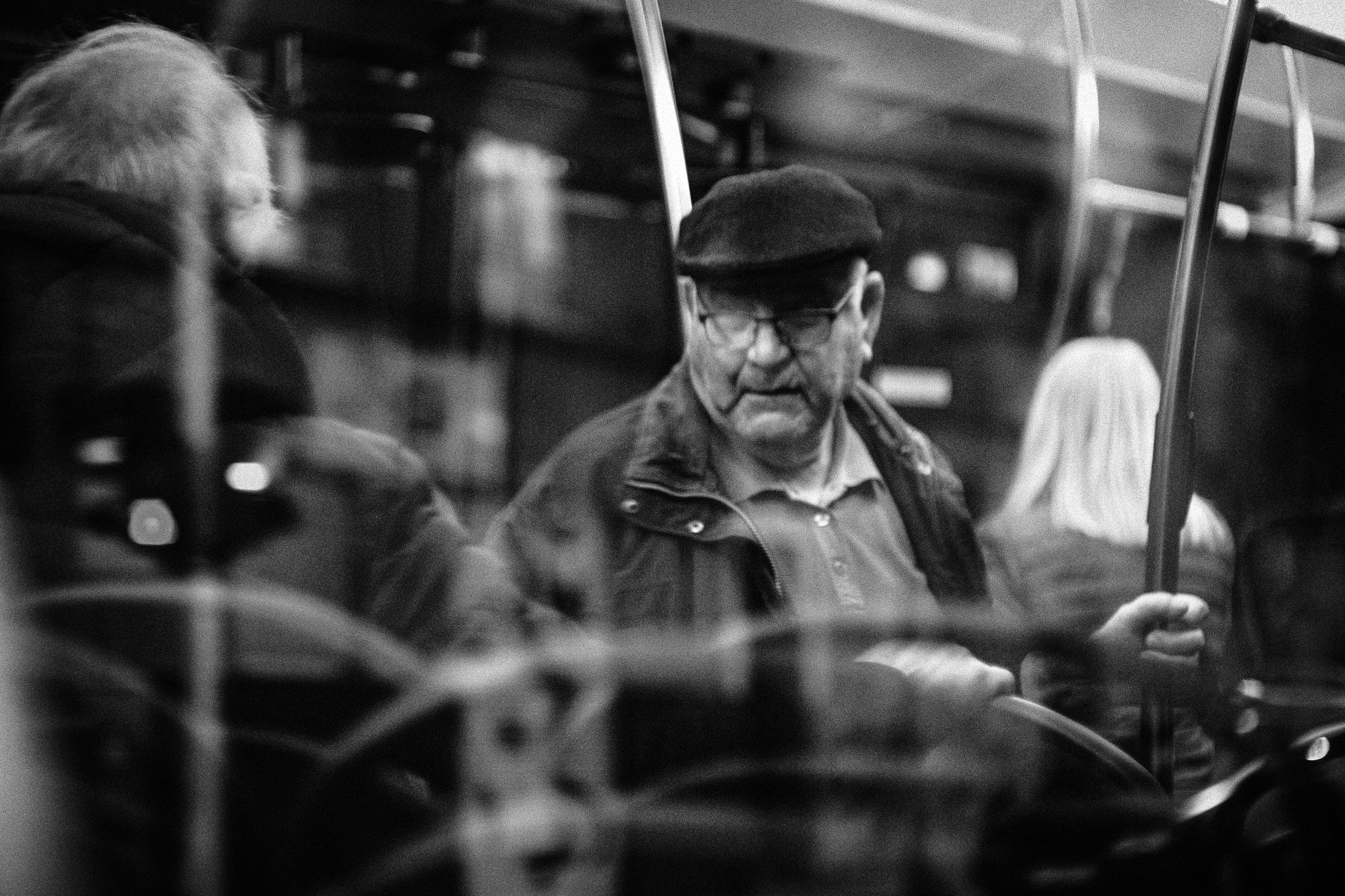 Black and white photo capturing an older man on a bus, reflecting public transit life.