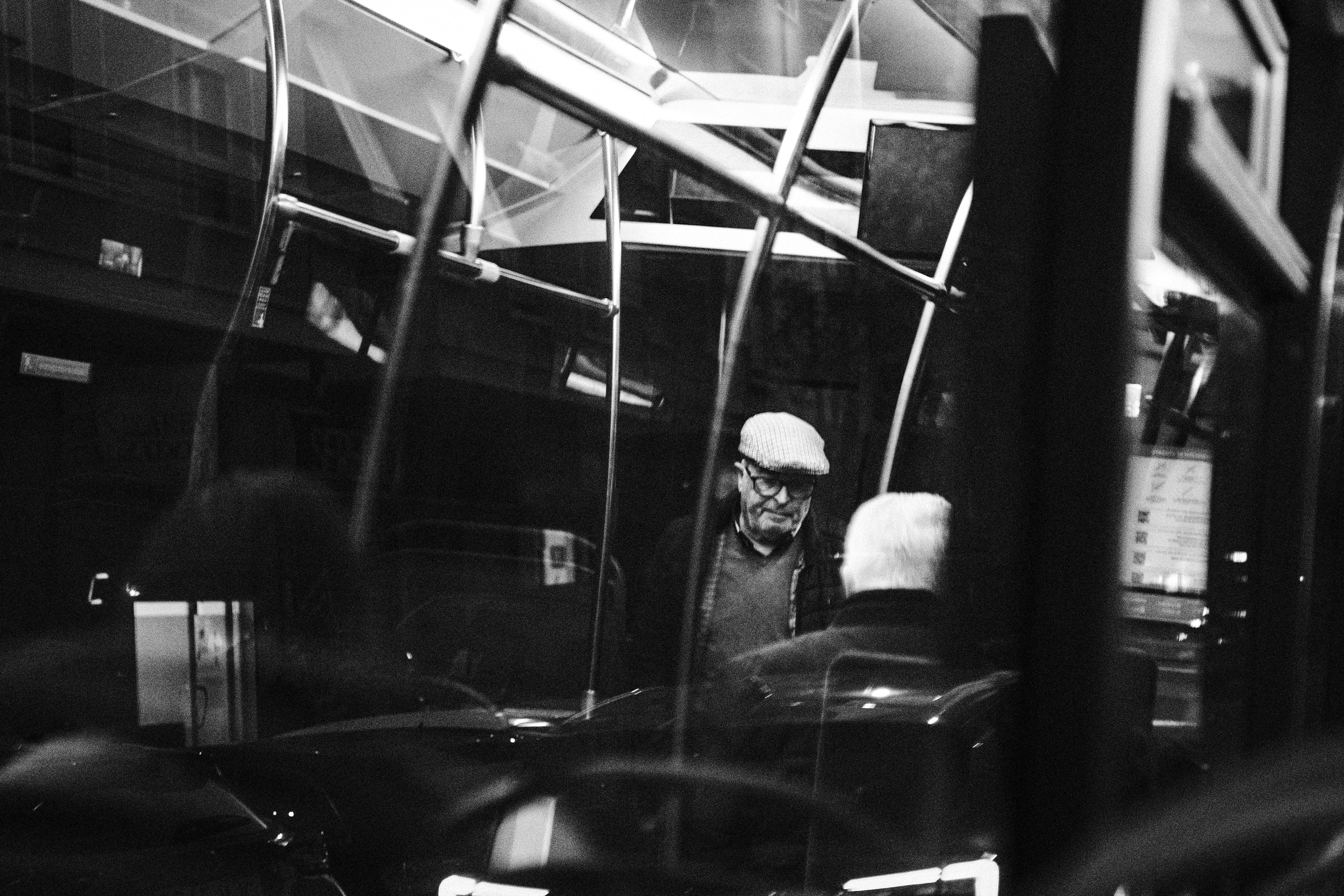 Candid black and white photo capturing conversations inside a bus.