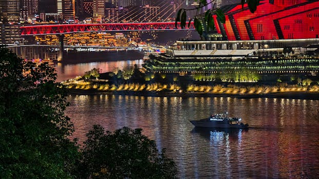A stunning nighttime cityscape featuring a vibrant illuminated bridge and a reflective river scene.