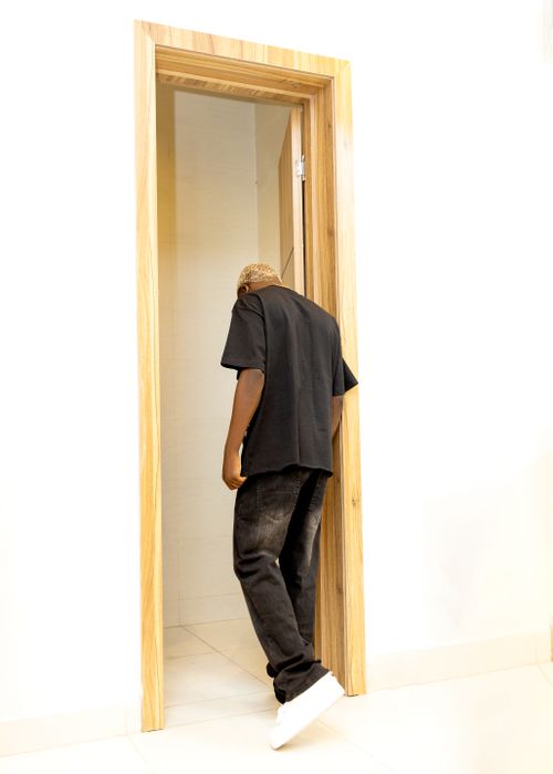 Free Casual person entering a room through a wooden doorway. Minimalist indoor scene. Stock Photo